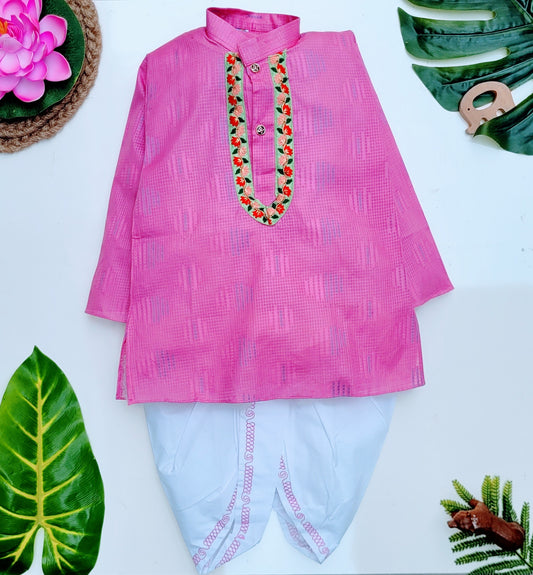 A kids' ethnic cotton pink dhoti kurta set with a collar neck and front button closure, displayed on a white background accompanied by green and red leaves, and a white flower.